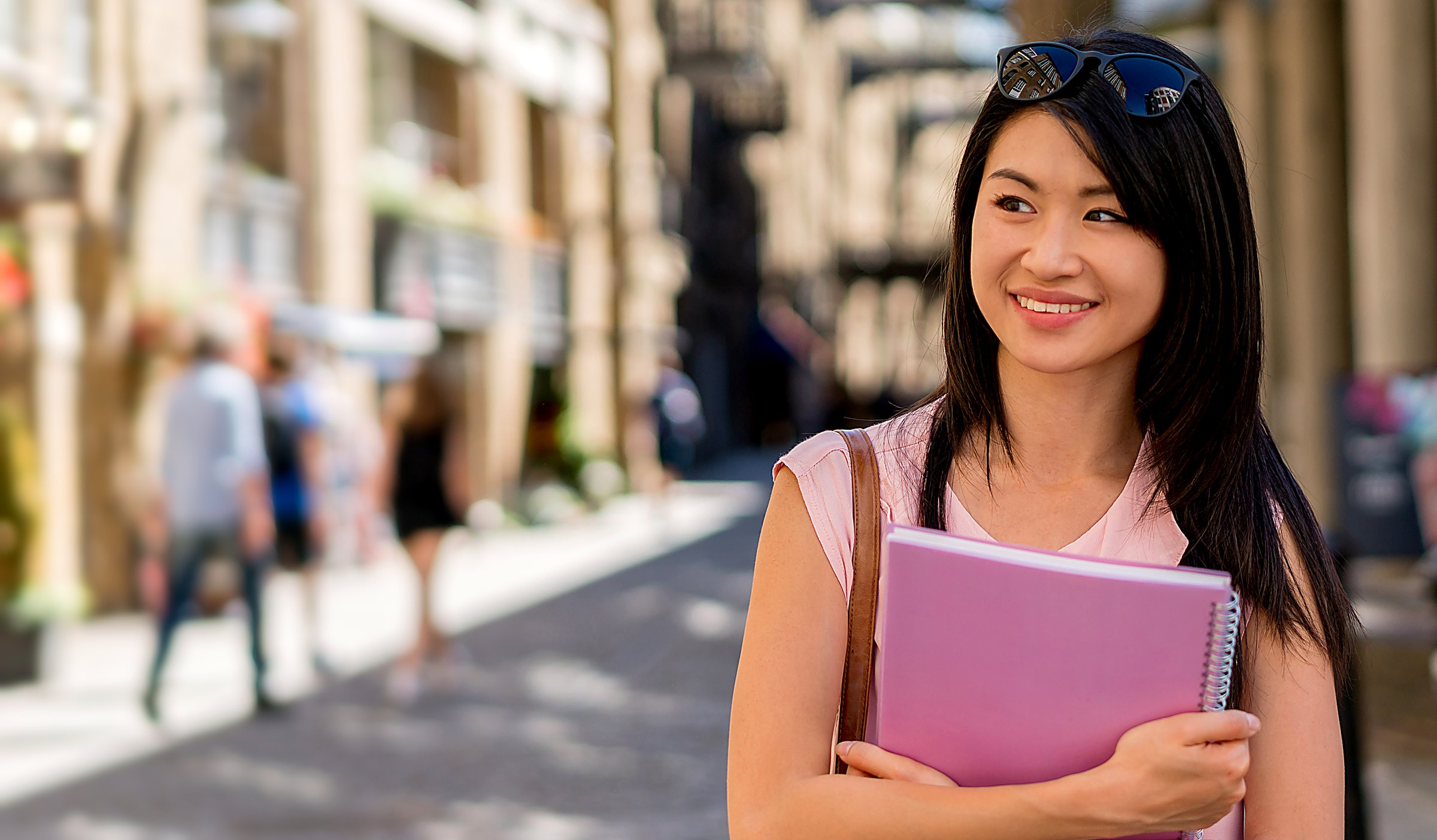 Smiling student holding notebooks, ready to learn English